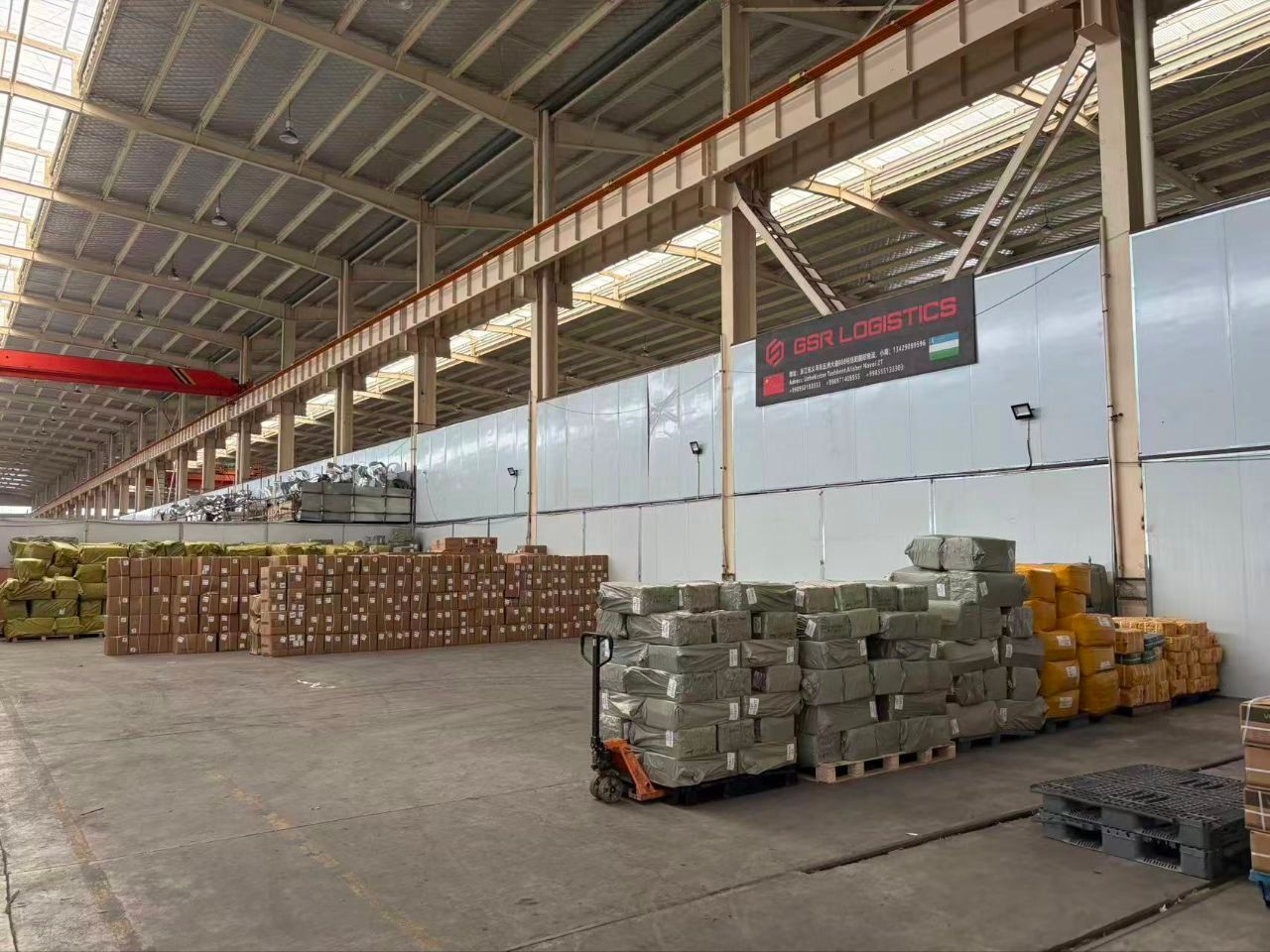Ivudagi qabul punkti: GSR Logistics banneri ostida poddonlarga terilgan yuklar